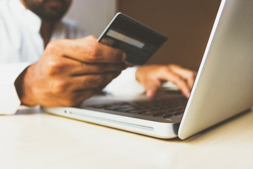 A person holding a credit card entering their details into a laptop