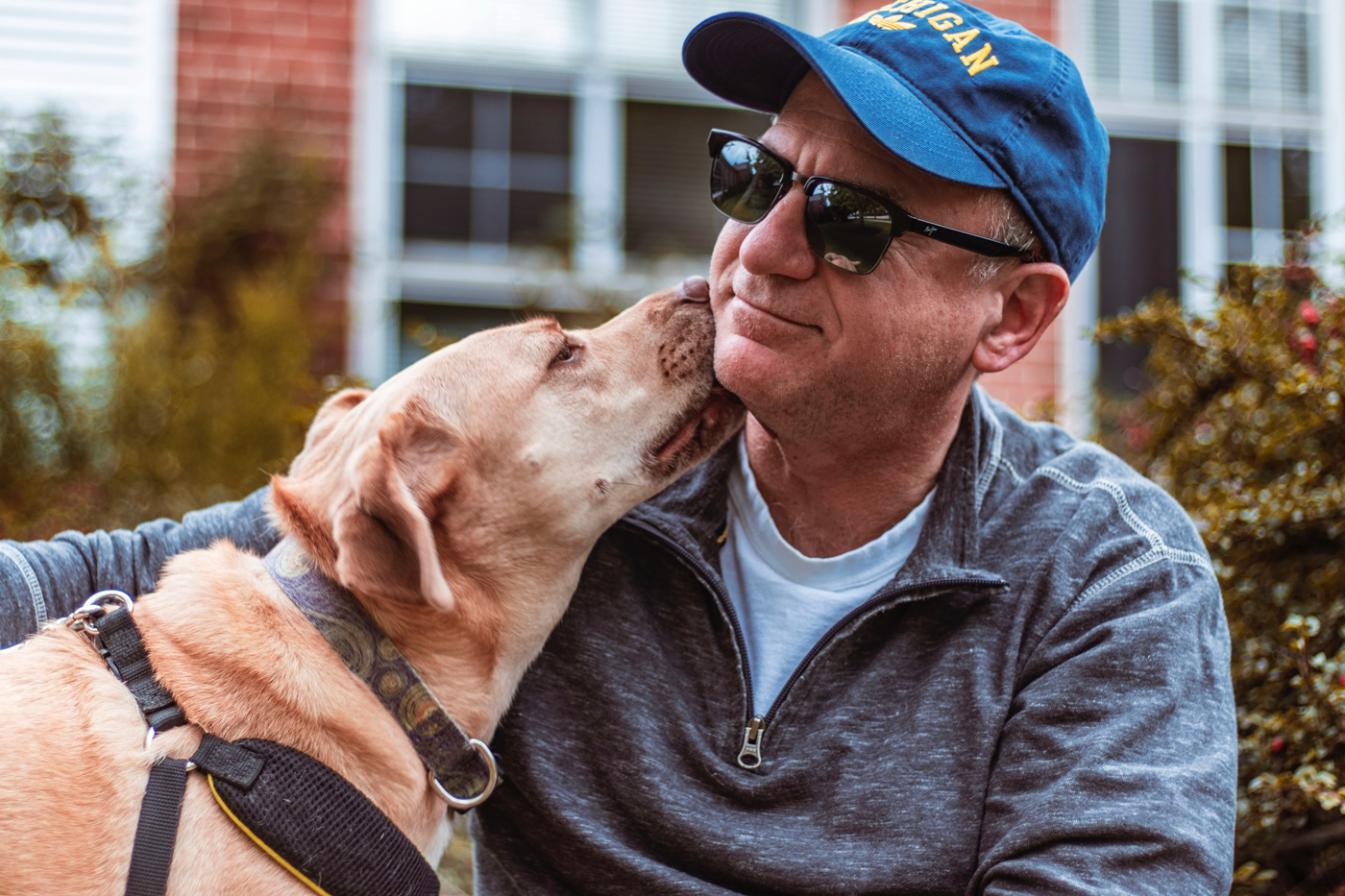 A dog licking its owners face while sitting outside